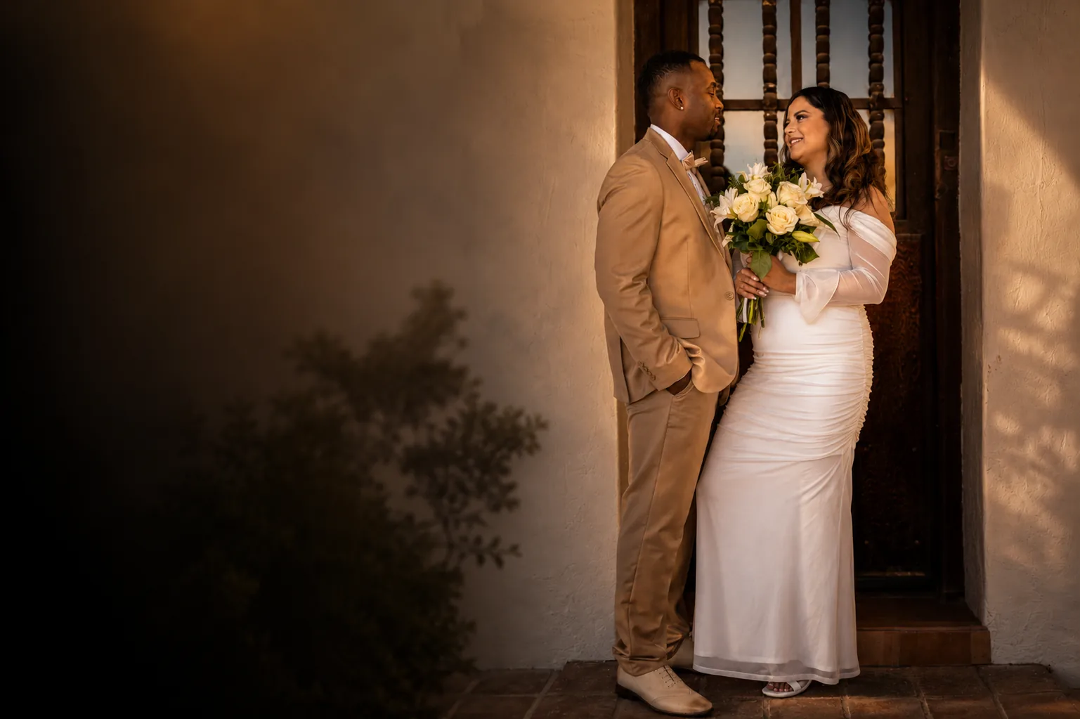 Bride and groom framed in a sunlit adobe doorway — a FitTechGuru photography moment.